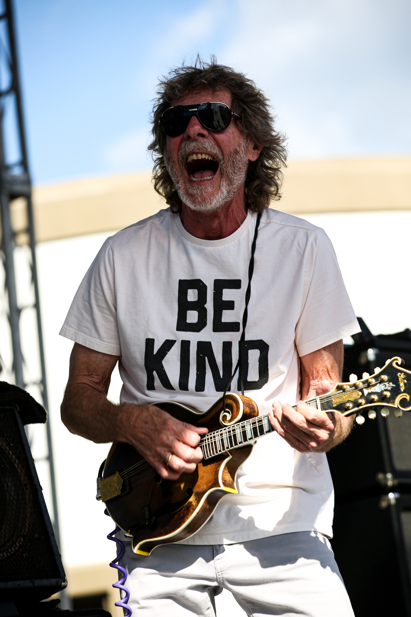 Sam Bush is known for bluegrass music and his be kind t shirts. 